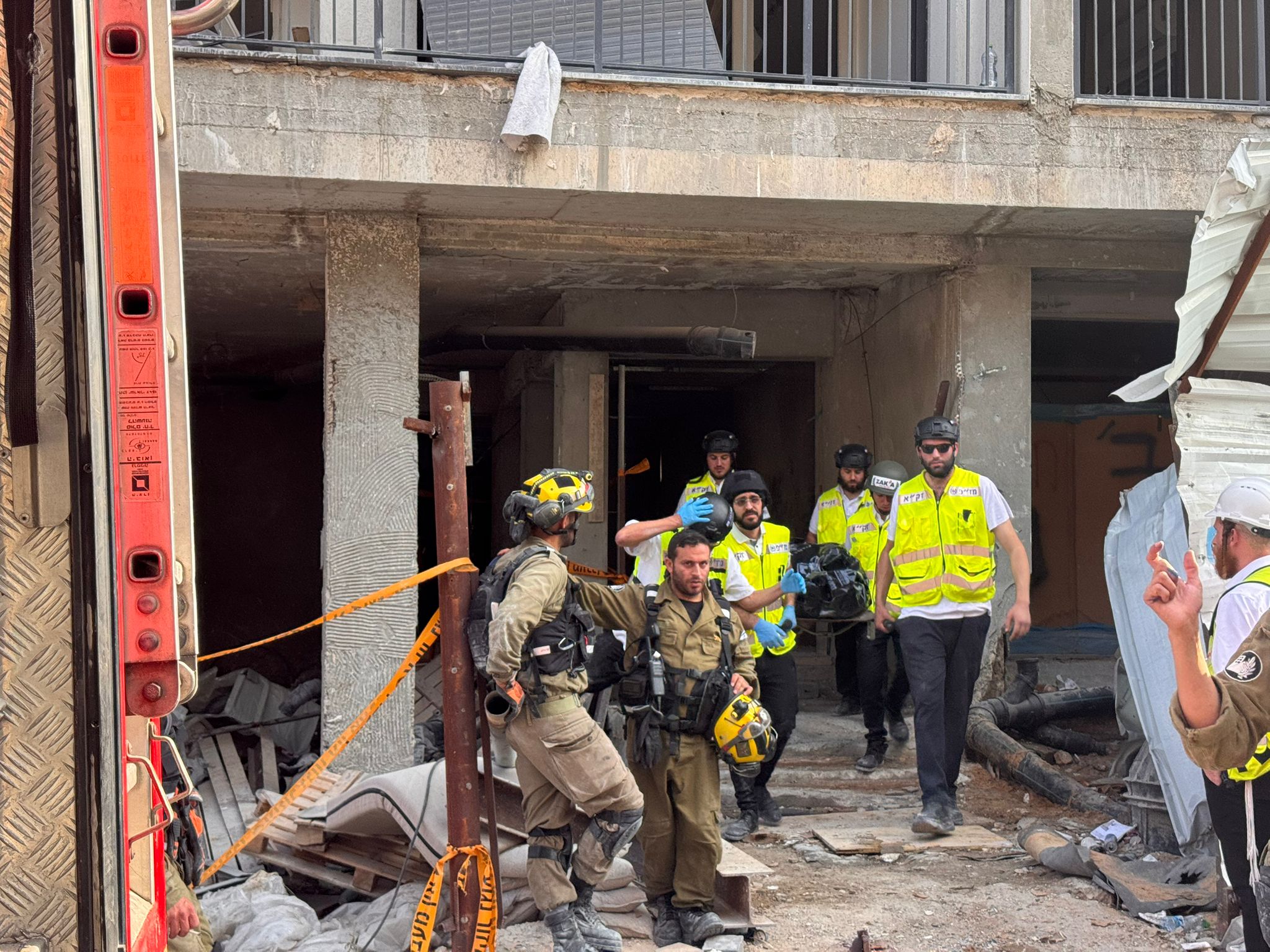 ZAKA volunteers carry their equipment out of a collapsed building after a response.