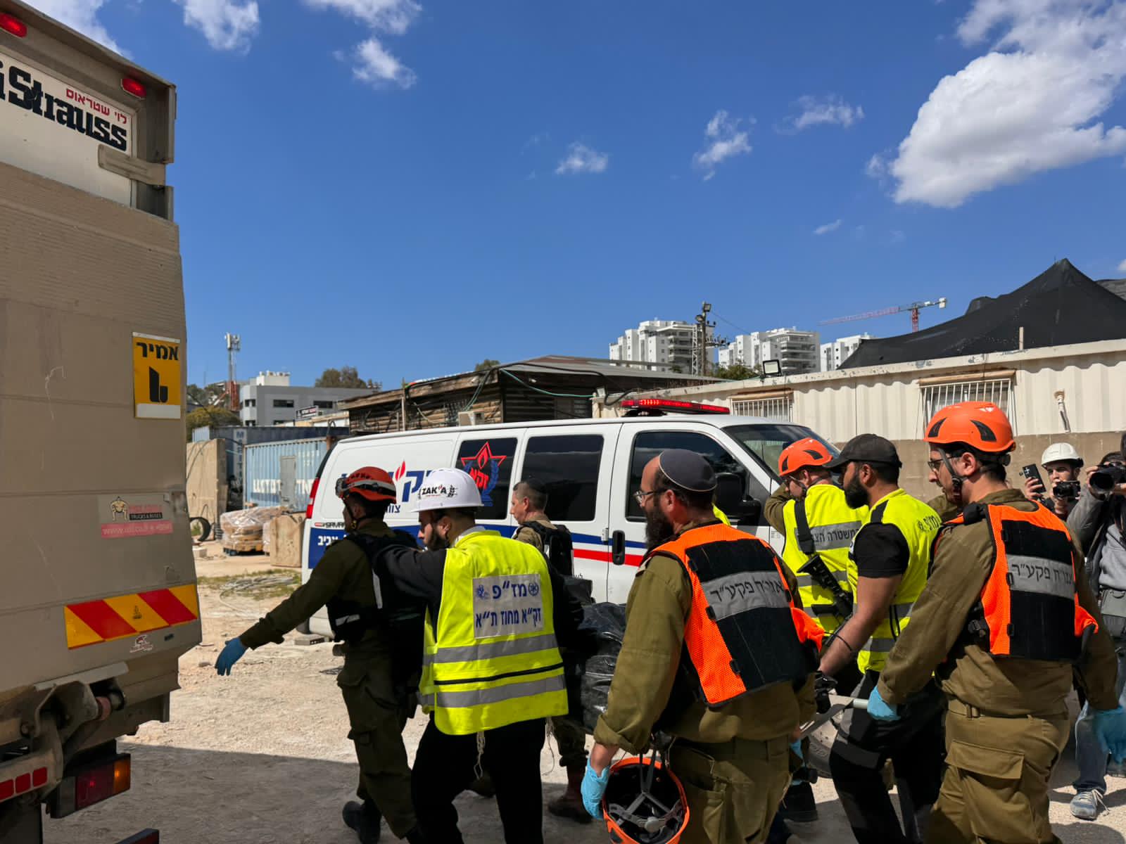 ZAKA volunteers and soldiers move together toward a response site under an open sky.